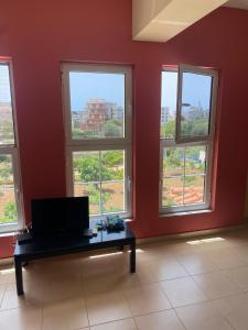 a room with four windows and a table with a television at Marina Apartaments in Himare