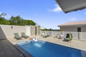 a swimming pool with chairs and a swan in the water at Villa Loiseau des îles in Les Anses-dʼArlets