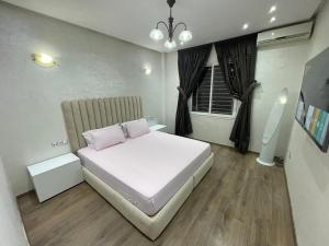 a bedroom with a white bed with two pink pillows at Luxueux Appartement Parc Champs de Cours avec Wifi Fibre 200 Mo in Fès