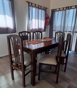 een houten eettafel en stoelen met ramen bij Cabañas Tinkuy I in Cortaderas