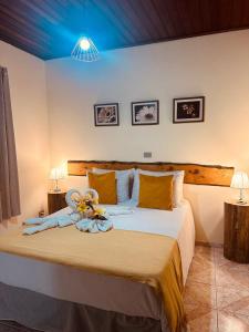 um quarto com uma cama com um ursinho de pelúcia em Pousada Valle do Sol em Campos de Jordão