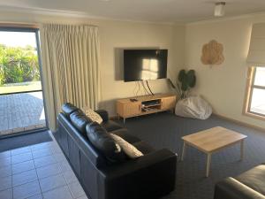 a living room with a couch and a tv at Shore Beats Work in Robe