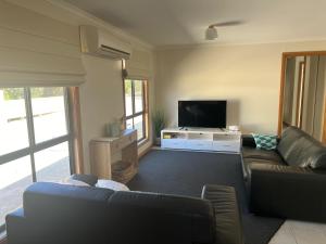 a living room with a couch and a flat screen tv at Shore Beats Work in Robe +10 photos