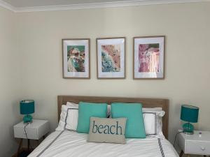 a bedroom with a bed with three pictures on the wall at Shore Beats Work in Robe