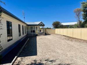 a house with a gravel driveway next to a fence at Shore Beats Work in Robe