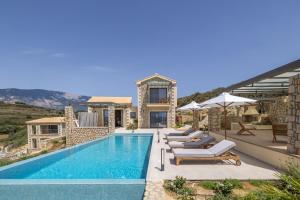 a villa with a swimming pool and lounge chairs at Zeus Luxury Villas - Villa Poseidon in Kefallonia
