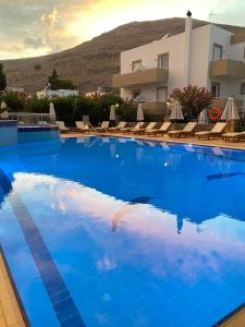 a large blue swimming pool with chairs and a building at Lindos Athena in Lindos