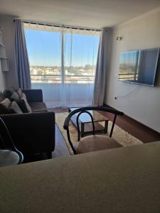 a living room with a couch and a table and a window at Hermoso y cómodo departamento en edificio in Calama