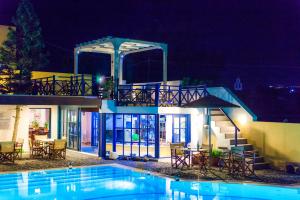 a house with a swimming pool at night at Kalimera Hotel in Akrotiri