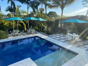 a swimming pool with two blue umbrellas and chairs at Casa Campestre Las Palmas in Pereira