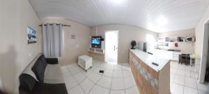 a room with a kitchen with a couch and a tv at Casa temporada Araçoiaba in Araçoiaba