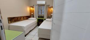 a small room with two beds and a refrigerator at Casa temporada Araçoiaba in Araçoiaba