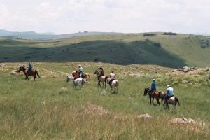 a group of people riding horses in a field at Elandskloof Trout Farm in Dullstroom