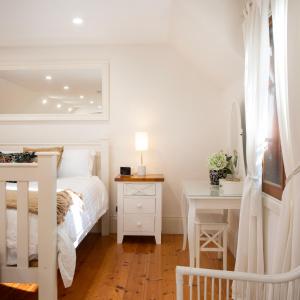 a white bedroom with a bed and a desk at Aldgate Creek Cottage in Aldgate