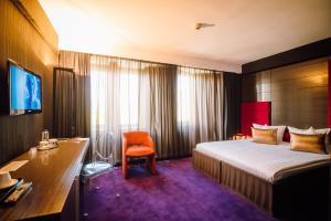 a hotel room with a bed and a desk at Plaza V Hotel in Târgu-Mureş