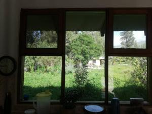 ein Fenster mit drei Ansichten eines Grasfeldes in der Unterkunft Casa en el campo in Quillacollo