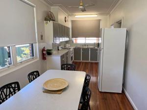 a kitchen with a table and a white refrigerator at Conns Cottage - Bring your own linen in South West Rocks