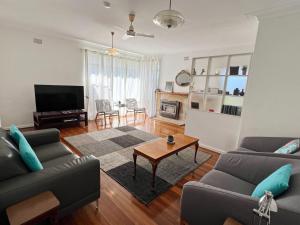 a living room with two couches and a television at Conns Cottage - Bring your own linen in South West Rocks