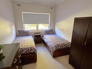 a bedroom with two beds and a window at Conns Cottage - Bring your own linen in South West Rocks