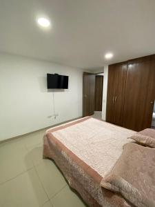 a bedroom with a large bed and a flat screen tv at Espectacular casa en Manizales in Manizales