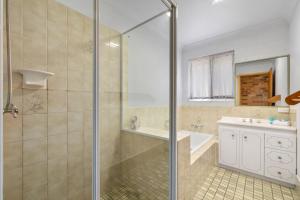 a bathroom with a shower and a tub and a sink at Sunset House on the Hill in Kingscliff