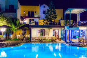 a swimming pool in front of a house at night at Kalimera Hotel in Akrotiri