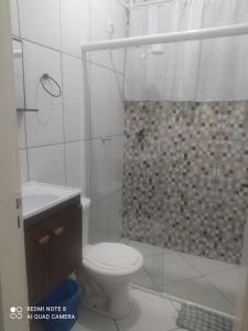 a white bathroom with a toilet and a shower at Pousada Quarto Aconchegante Suite com garagem perto da basílica in Aparecida