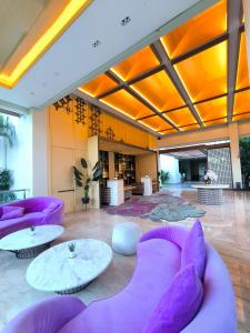 a lobby with purple chairs and tables in a building at ILLIRA Lite Praya Lombok in Praya