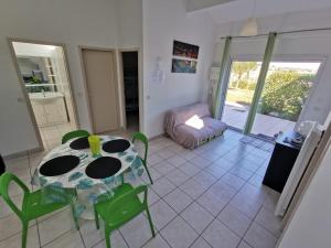 a dining room with a table and green chairs at Gîte Soleil in Adissan
