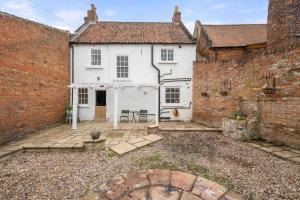 Una vista exterior de una casa blanca con una pared de ladrillo. en Monument House Horncastle, en Lincolnshire
