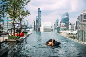 a man swimming in a infinity pool in a city at Sindhorn Midtown Hotel Bangkok, Vignette Collection by IHG in Bangkok