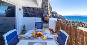 a table with a bowl of fruit and wine glasses at Oceanfront Oasis By Dream Homes Tenerife in Acantilado de los Gigantes