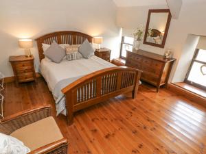 a bedroom with a large bed and wooden floors at Inglenook Cottage in Haverfordwest