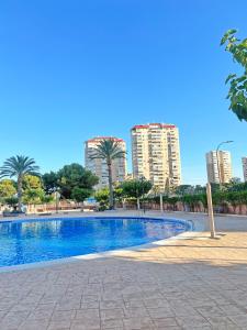 a swimming pool with palm trees and tall buildings at Coqueto con PISCINA, nuevo a 50m del mar, Parking Gratis in El Campello