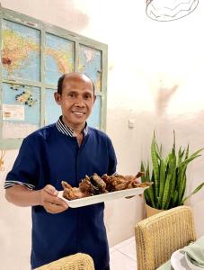 a man is holding a plate of food at Umalas Retreat - Private Villa with Cook in Kerobokan