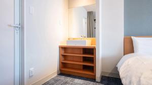 a bathroom with a sink next to a bed at Vessel Hotel Kurashiki in Kurashiki