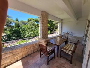 a balcony with a wooden table and chairs and a large window at Margaret 150 METERS TO THE BEACH in Banjole