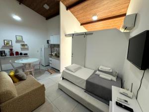 ein Wohnzimmer mit einer Couch, einem Fernseher und einem Tisch in der Unterkunft Solar Agua Flats Elegance Flat in Pipa