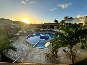 ein Pool mit Stühlen und ein Sonnenuntergang im Hintergrund in der Unterkunft Solar Agua Flats Elegance Flat in Pipa