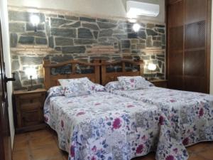 una camera da letto con due letti e un muro di pietra di Apartamentos Rurales Tierras de Granadilla a Zarza de Granadilla