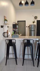a kitchen with a counter with three bar stools at D' Tanjung Homestay-Orked in Pekan