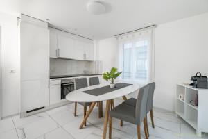 una cucina bianca con tavolo e sedie di Ferienwohnungen mit Gratis Parkplatz Eichen ad Arbon