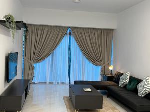 a living room with a black couch and large windows at Eaton Residence Suites KLCC in Kuala Lumpur
