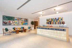 Eine Lobby mit zwei Personen, die an einem Tresen sitzen. in der Unterkunft Rove JBR in Dubai