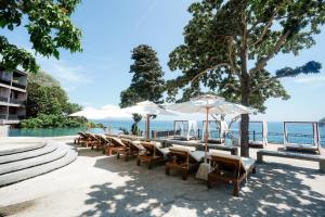 a row of chairs and umbrellas next to the water at Dusit Buncha Koh Tao by Riya Group in Ko Tao