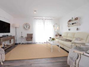 a living room with a couch and a clock on the wall at Nausikaa's- Fleur de Lis in Groß Schwansee