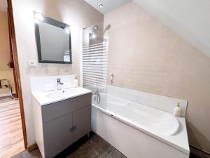 a bathroom with a sink and a bath tub and a mirror at La longère T3 - Au Golf de Bellême - Parking - Wifi - 4 Pers in Bellême +11 photos