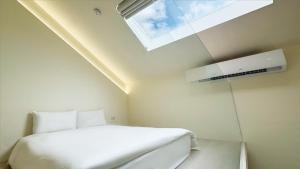 Un dormitorio con una cama blanca y una ventana. en Longtan Lake Inn, en Jiaoxi