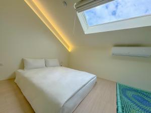 Una cama blanca en una habitación con ventana. en Longtan Lake Inn, en Jiaoxi