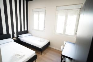 a small room with two beds and two windows at Adventure Hostel Madrid in Madrid